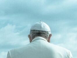 person wearing white cap looking down under cloudy sky during daytime
