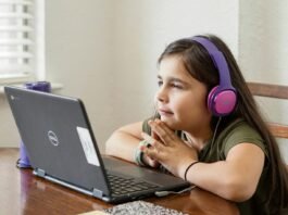 a little girl sitting at a table with a laptop